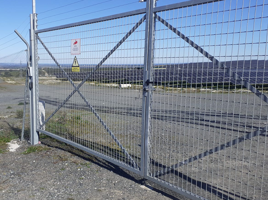 Grande double porte métallique du parc solaire équipée d’un système de verrouillage électronique.