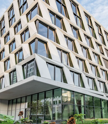 Architecture moderne de l’immeuble de bureaux du projet ONE PLAZA avec une façade distinctive et de grandes surfaces vitrées.